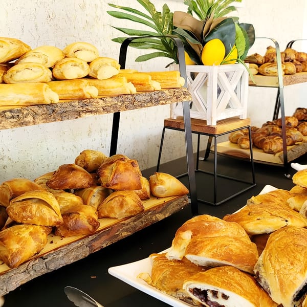 A buffet table with three tiers of various Italian pastries and baked goods on wooden planks.