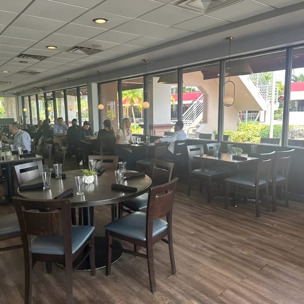 Diners seated at tables in Carmela's Italian restaurant, with large windows overlooking an outdoor area.
