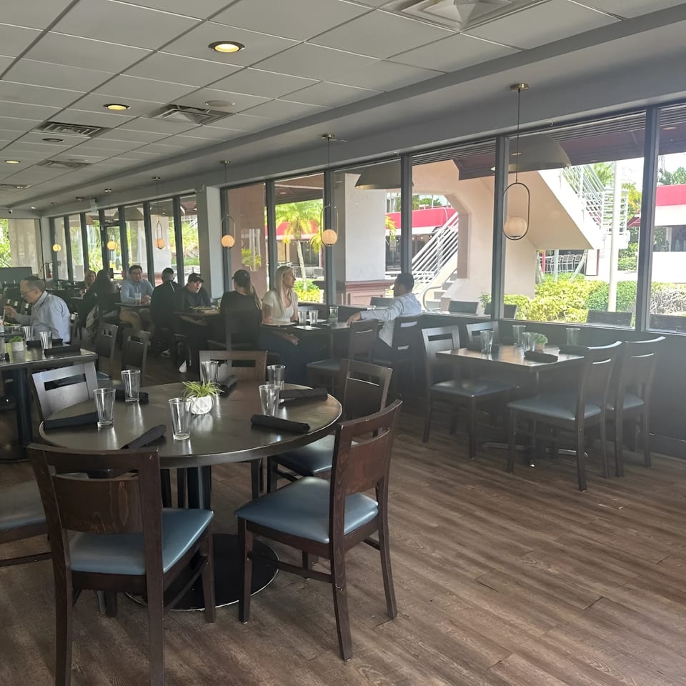 Diners seated at tables in Carmela's Italian restaurant, with large windows overlooking an outdoor area.