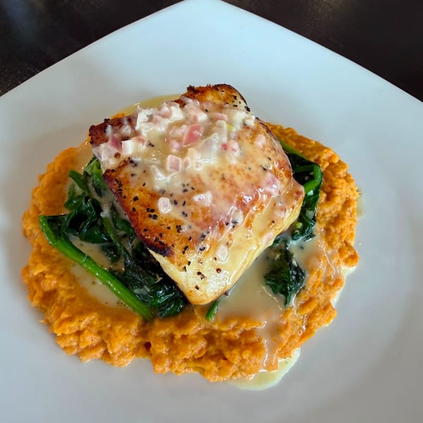 Pan-seared fish with creamy sauce, spinach, and sweet potato mash on a white plate.